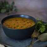 Masala Dal in a black bowl with spoons on the right side