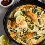 Creamy Lemon Chicken with Spinach in a black cast iron pan with lemon on the left bottom and paprika top left