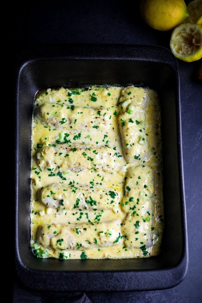 Baked fish with lemon butter sauce in a black dish