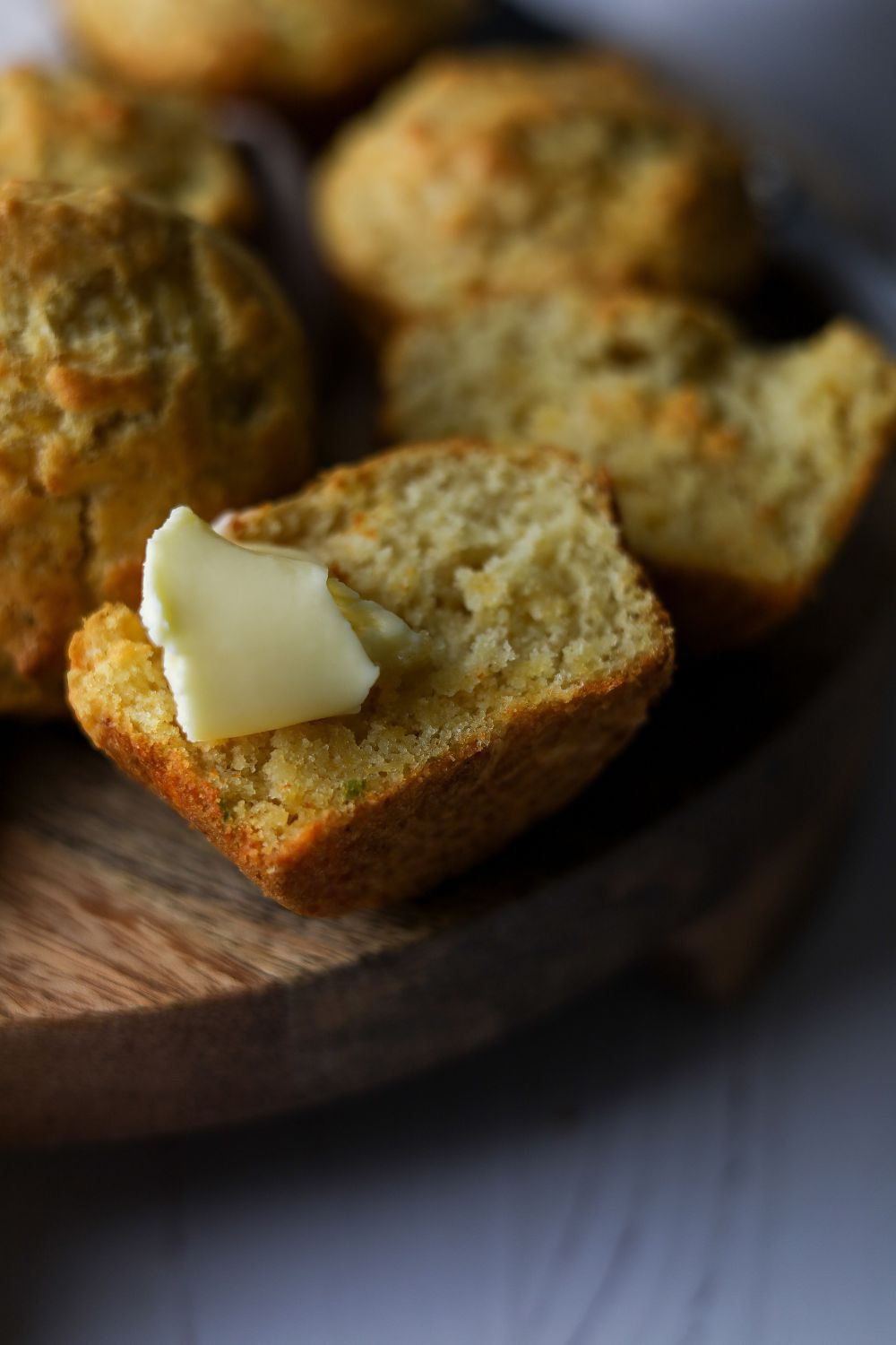Muffin cut in half with a blob of butter on the piece on the left
