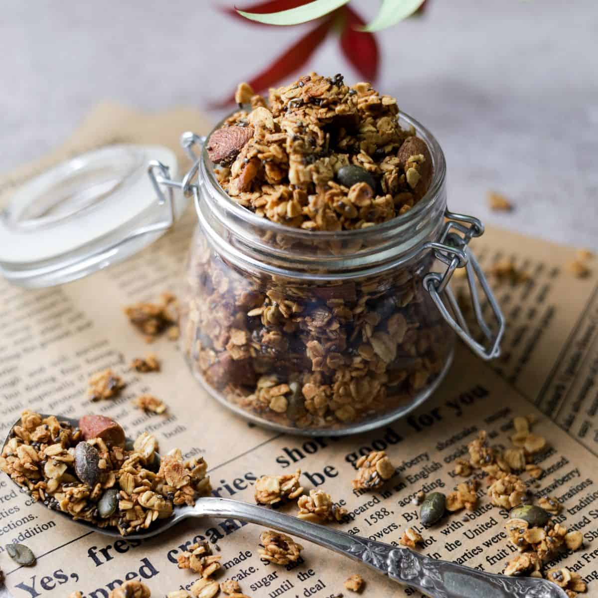 Crunchy Homemade Granola in a jar with a spoon filled with granola in front